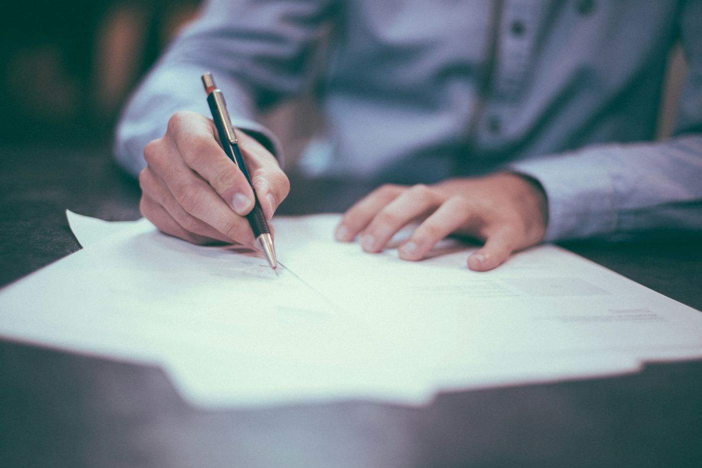 Business owner writing and reviewing financial paperwork with a pen
